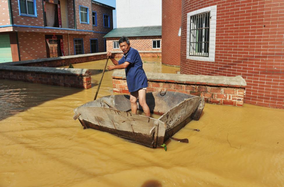 A man rows on a flooded area in Poyang County, Jiangxi province